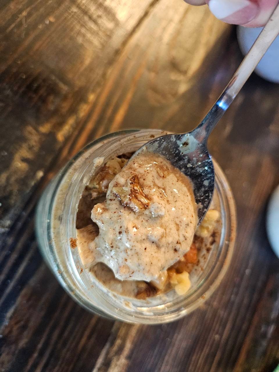 Overhead view of a spoonful of creamy apple pie overnight oats in a glass jar