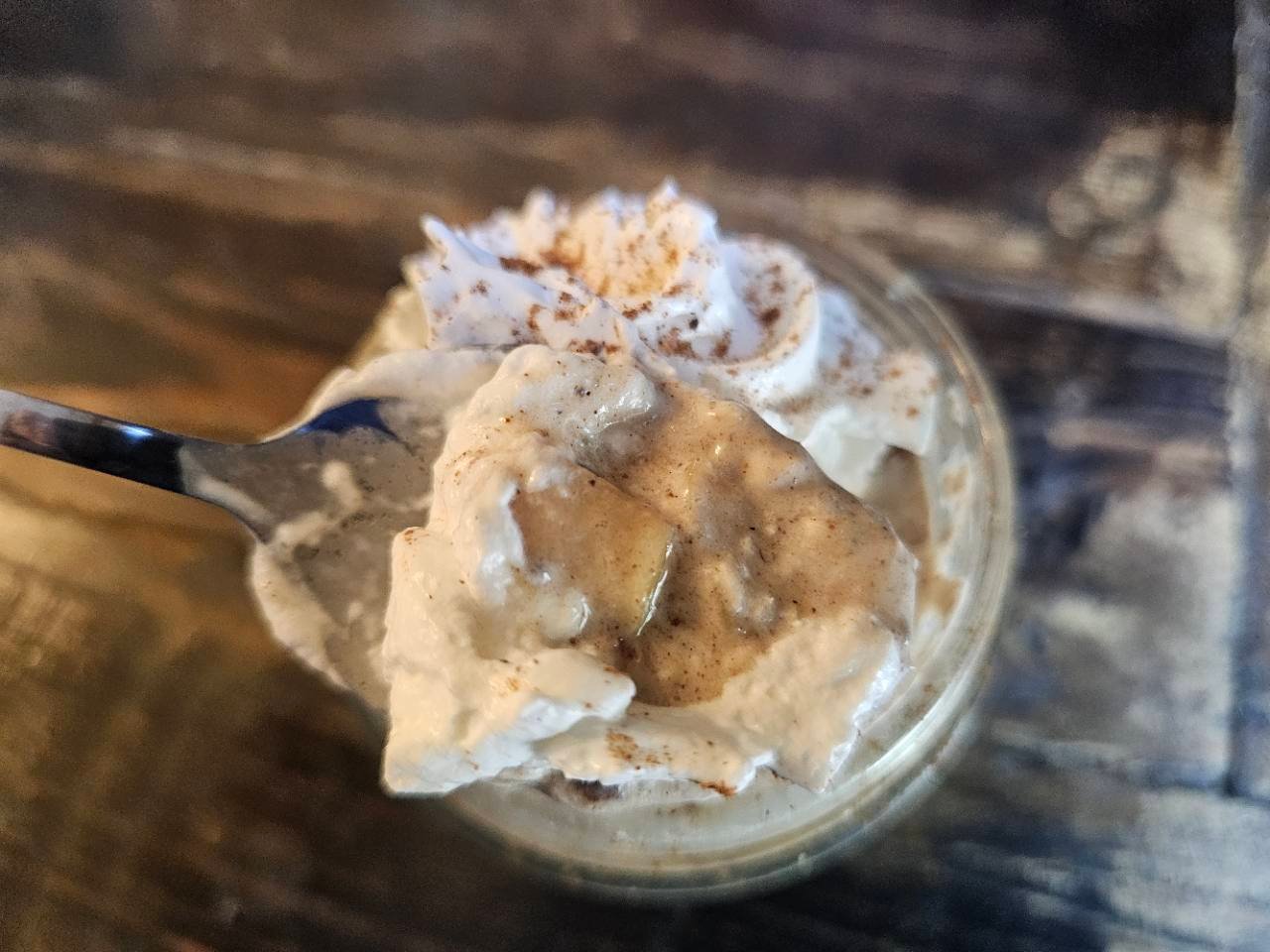 Spoonful of creamy apple pie overnight oats above a glass jar