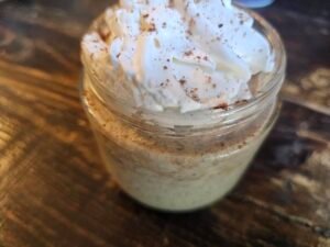 Glass jar of apple pie overnight oats topped with whipped topping and cinnamon